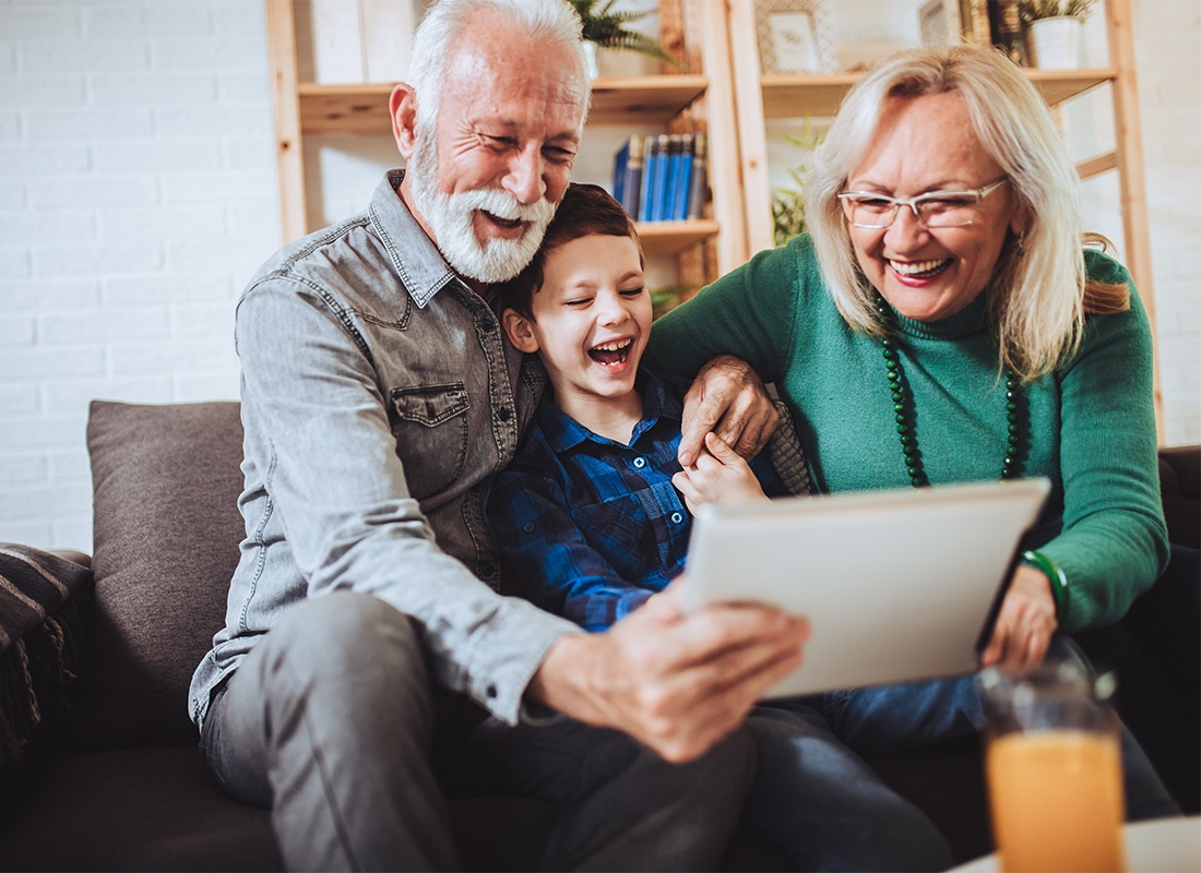 Read Our Reviews - Portrait of Cheerful Grandparents Having Fun Sitting with Their Young Grandson on the Sofa While Watching Videos on a Tablet